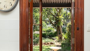 Une porte en bois qui donne sur un jardin, avec une horloge accrochée au mur.