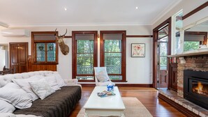 Un salon avec une cheminée, un canapé, une table basse et une tête de cerf accrochée au mur.