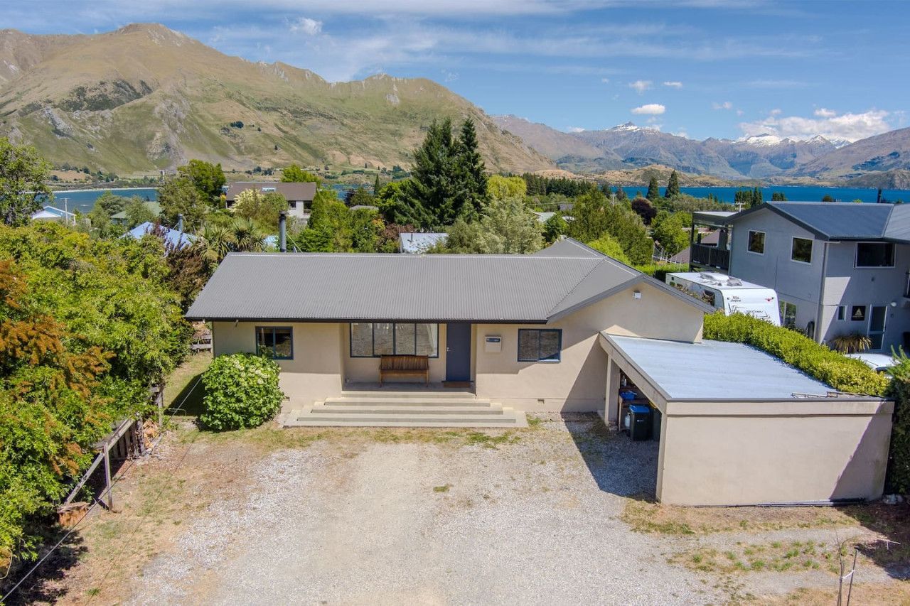 Een modern huis met een plat dak, een veranda en uitzicht op bergen en een meer.