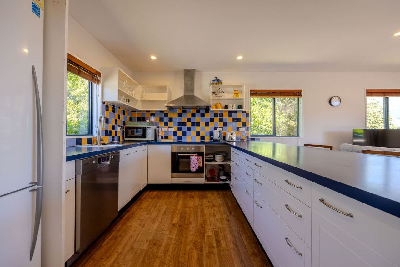 Een moderne keuken met witte kasten, een RVS vaatwasser, een magnetron en een fornuis.