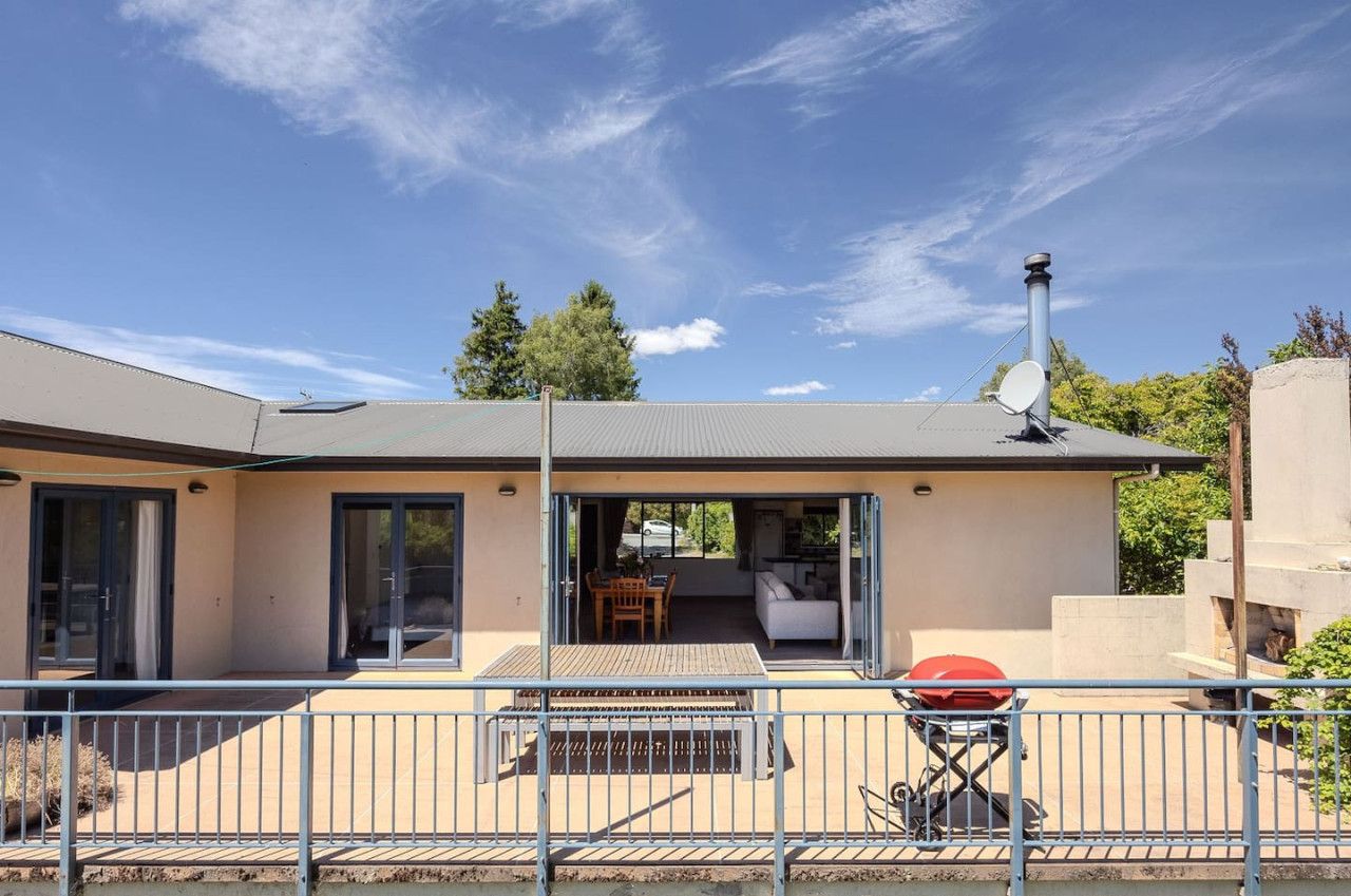 Een modern huis met terras, schuiframen, een barbecue en een schotelantenne.