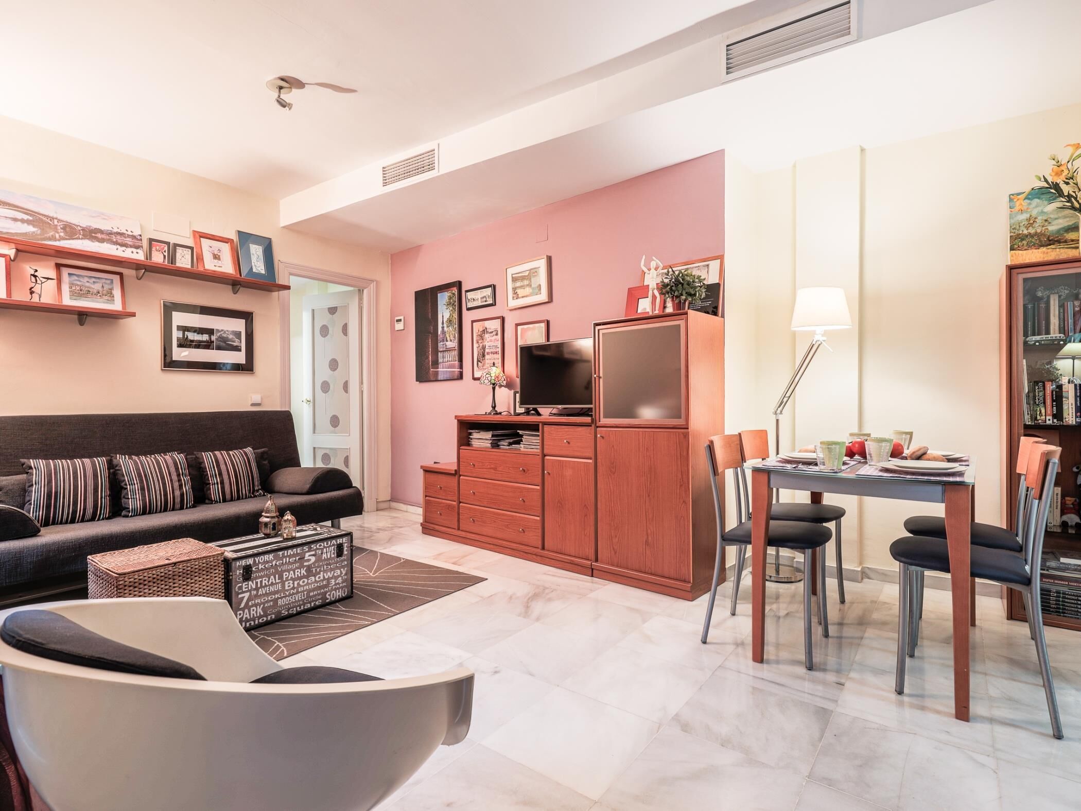 A living room with a sofa, coffee table, TV, and a dining area with chairs and a table.