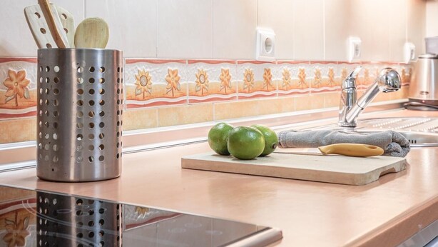 A kitchen with a stainless steel utensil holder, a cutting board with green bell peppers, and a sink with a faucet. - Sevilla Best Location Triana Apartment (Sevilla)