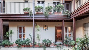 Un immeuble de deux étages doté de balcons, de plantes en pot et d’une cour pavée.