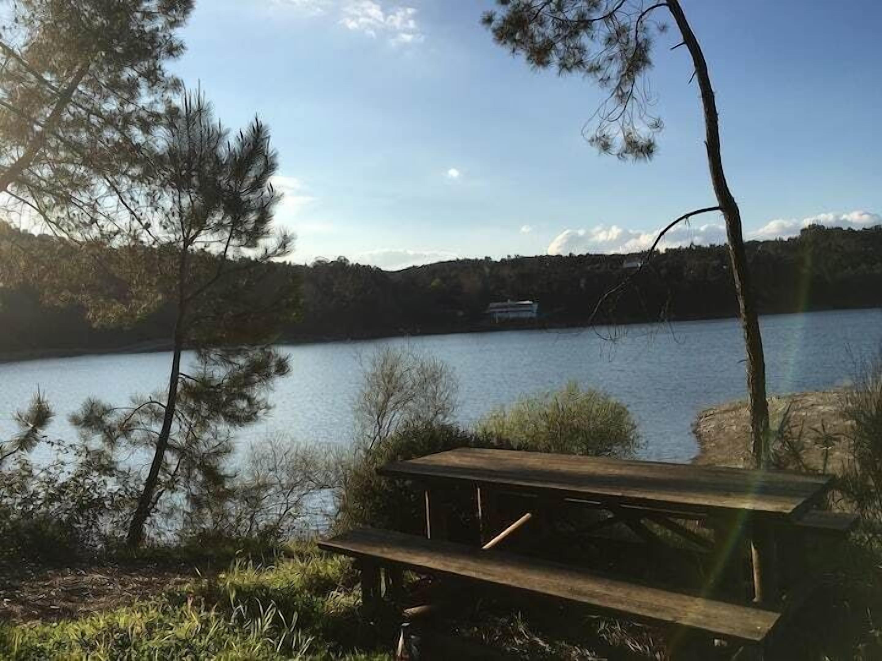 Picknicktafel aan het meer met uitzicht op het water en gebouwen in de verte.