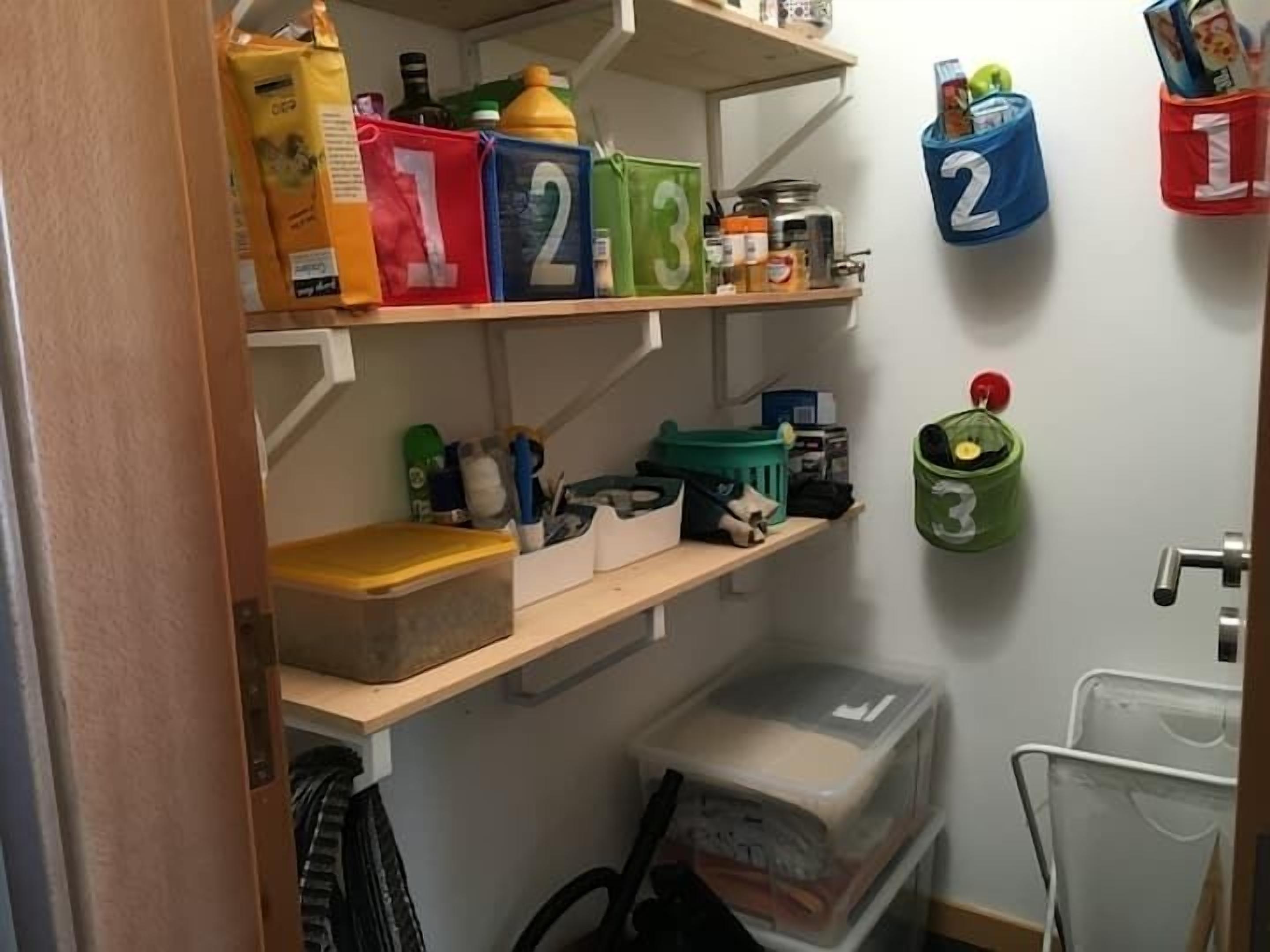 A storage area with labeled bins and shelves, containing various items like bottles and containers.