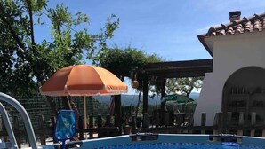 A swimming pool with a ladder, surrounded by lounge chairs and umbrellas.