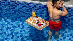 A poolside view with a tray of food and drinks. - TGT BEACH HOTEL (Da Nang)
