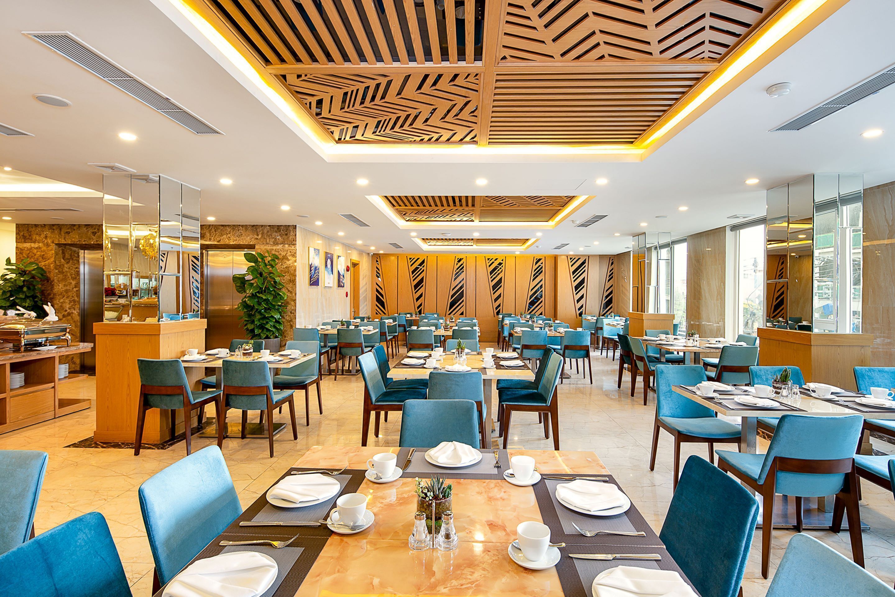 A spacious dining area with multiple tables and chairs, a modern ceiling design, and a well-lit environment.