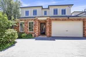 A two-story house with a garage, brick facade, and a large driveway. - Tranquil Escape by Ready Set Stay - Beach, shops, internet, Foosball (Dromana)
