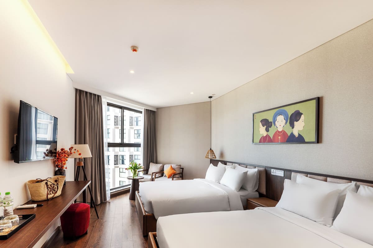 A hotel room with two beds, a desk with a lamp, a TV, and a window with curtains.