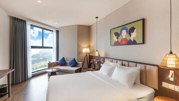 A hotel room with a large bed, a desk, a chair, a small table, a lamp, and a painting on the wall.