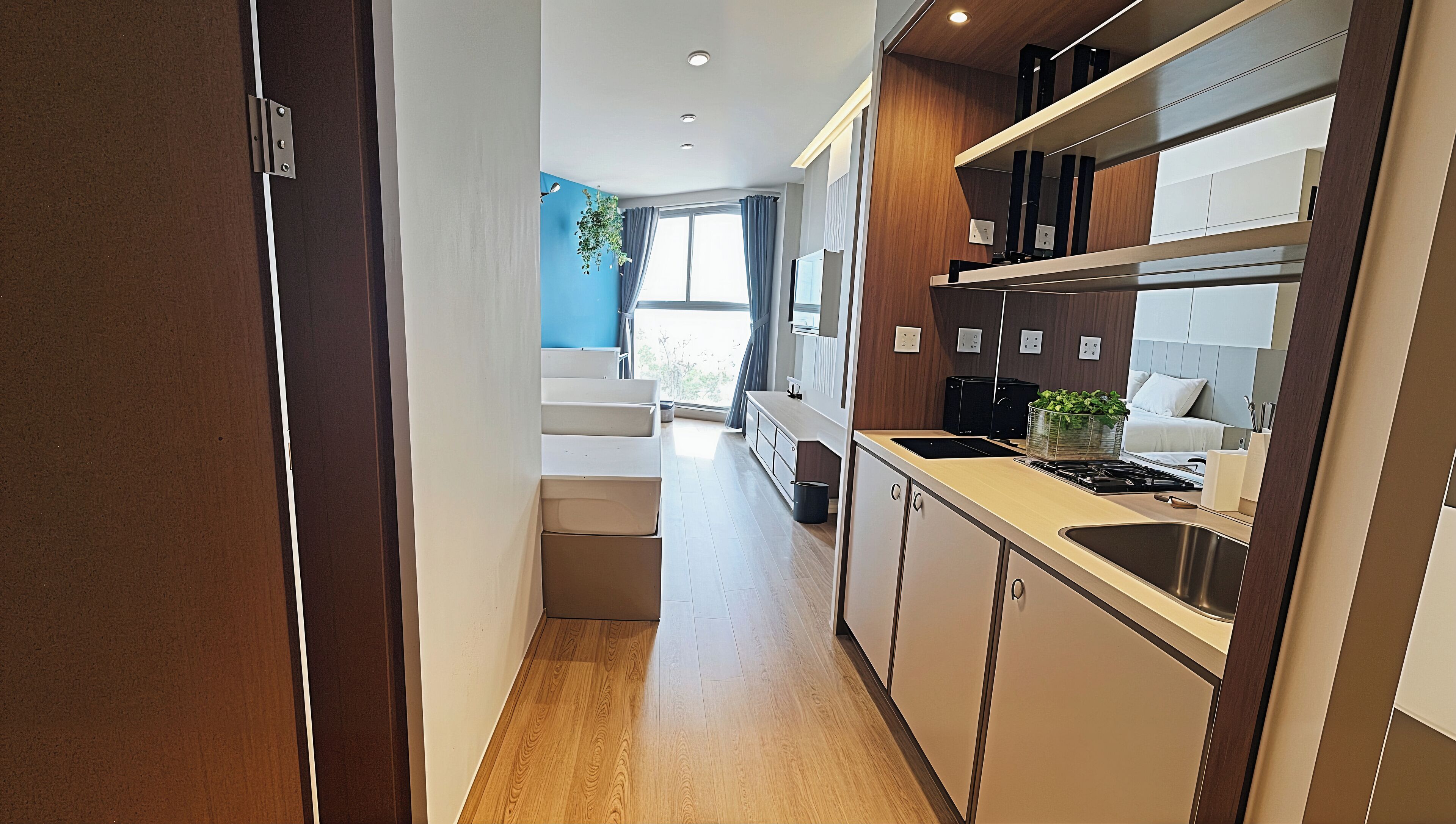 A modern kitchen with a wooden floor, built-in cabinets, a stove, and a window with curtains.