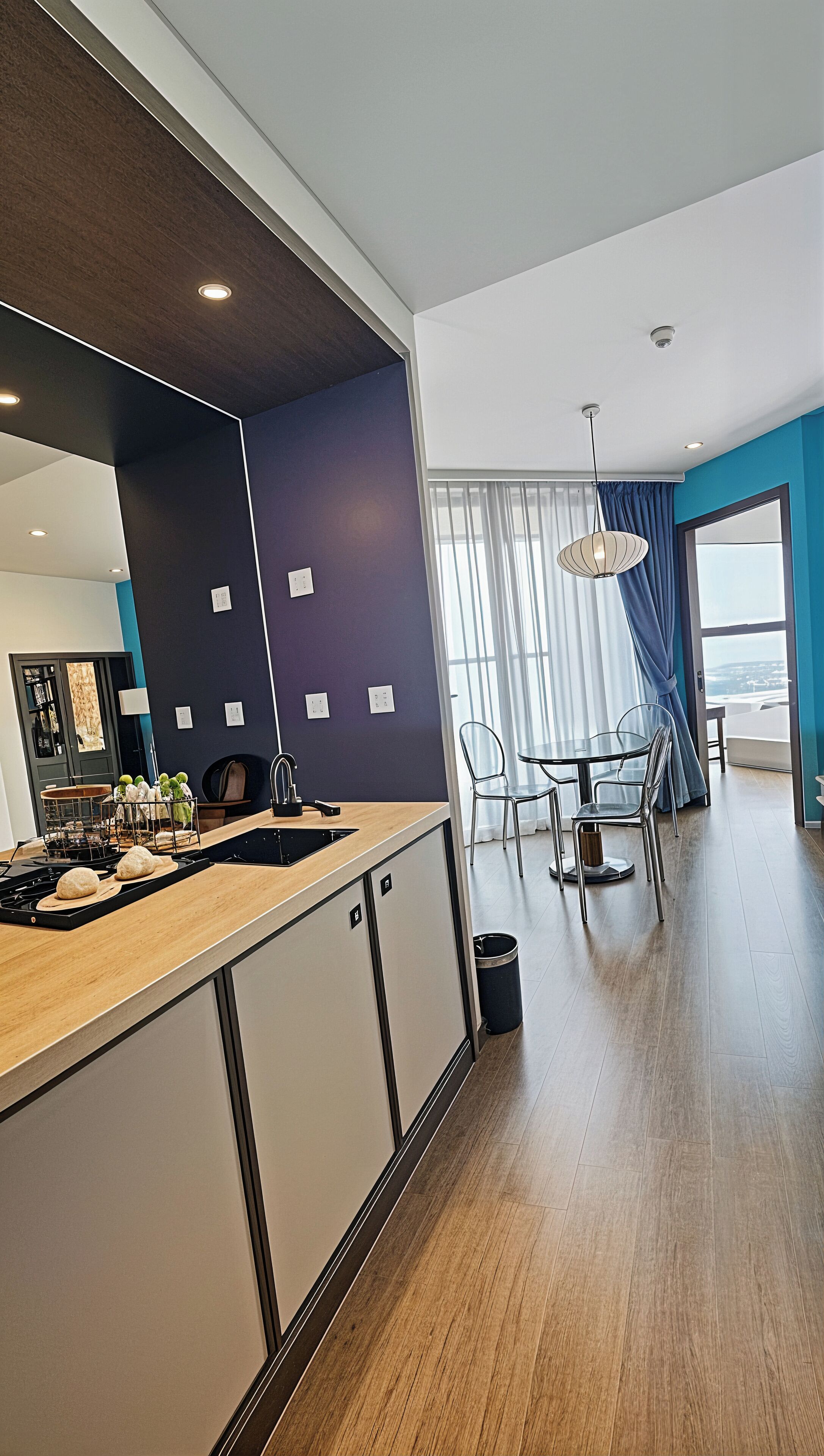 A modern kitchen with a central island, a dining area with a table and chairs, and a view of the city through large windows.