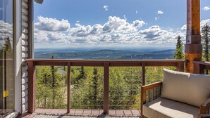 A balcony with a wooden railing, a cushioned bench, and a view of a mountainous landscape. - Norrsken View - Sauna - Mountains - Deck - Aurora - Family Friendly - Wifi (Fairbanks)