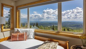 A bedroom with a large window offering a scenic view of a forested landscape. - Norrsken View - Sauna - Mountains - Deck - Aurora - Family Friendly - Wifi (Fairbanks)