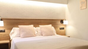 A neatly made bed with white linens and pillows, a wooden headboard, and two wall-mounted bedside lamps. - Sagrada Familia Apartment 14 (Barcelona)