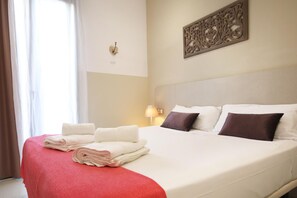 A neatly made bed with white and brown pillows, a red bedspread, and folded towels on the side. - Sagrada Familia Apartment 33 (Barcelona)