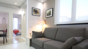 Ein modernes Wohnzimmer mit einem grauen Sofa, einem Beistelltisch mit einer Lampe und zwei gerahmten Bildern an der Wand.