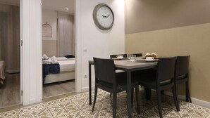 Une chambre d’hôtel avec un lit, une table à manger avec des chaises, une horloge murale et un sol à motifs.
