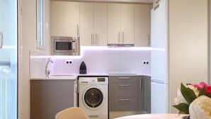 Une cuisine compacte équipée d’un lave-linge, d’un four à micro-ondes et d’une machine à café.
