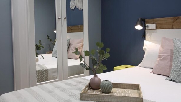 Une chambre à coucher avec un lit, une table de chevet et un miroir.
