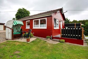 Un camper rosso con un cortile recintato, un'area salotto esterna coperta e un'antenna parabolica.