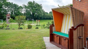 Una cama con dosel a rayas, pared de ladrillo y patio con un columpio.