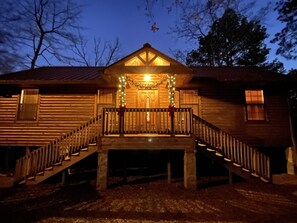 Eine Holzhütte mit einer Veranda, einer Treppe und einer dekorativen Lampe.
