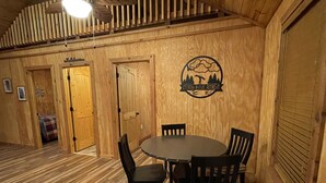 Un interior de madera con una mesa redonda y cuatro sillas, un ventilador de techo y un letrero que dice "Cypress Bayou Retreat".