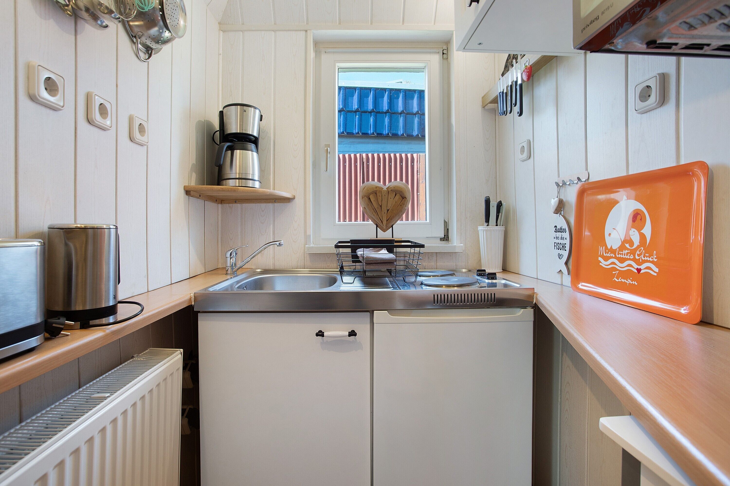 Eine kleine Küche mit Fenster, einer Kaffeemaschine, einem Toaster und einem Geschirrgestell.