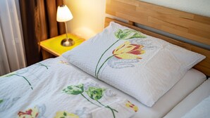 Un lit avec une literie à motifs floraux, une tête de lit en bois et une lampe de chevet.