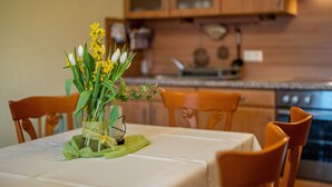 A dining table with a vase of flowers, wooden chairs, and a kitchen in the background. - Apartment 'Kreuzstube' with Mountain View and Wi-Fi (Biberach)