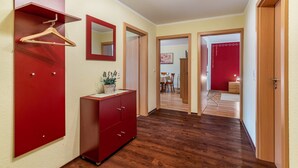 A hallway with a wooden floor, a red cabinet, a mirror, and a hanging garment. - Apartment 'Kreuzstube' with Mountain View and Wi-Fi (Biberach)