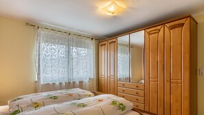 A bedroom with a bed, two bedside tables, a wardrobe, and a window with curtains. - Apartment 'Kreuzstube' with Mountain View and Wi-Fi (Biberach)