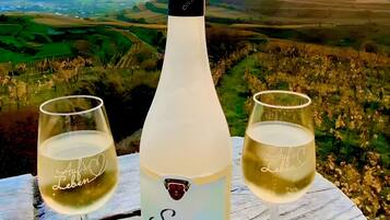 A bottle of Secco d'Oro wine with two glasses on a wooden table, set against a scenic landscape view.