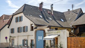 A traditional European building with a tiled roof, a large wooden gate, and a storefront with a sign. - Apartment 'Ferienwohnung Zur Weinsteige' with Wi-Fi (Ihringen am Kaiserstuhl)