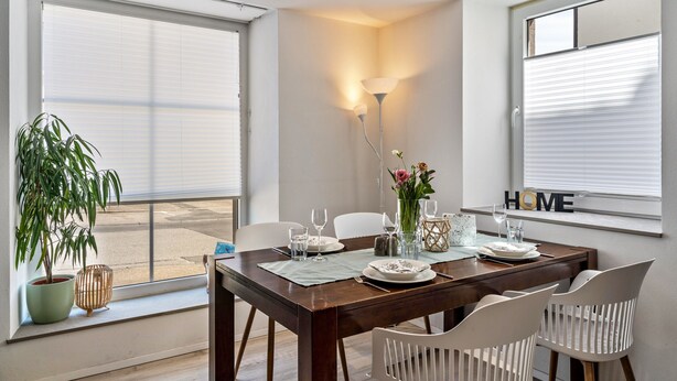 A dining area with a table set for four, a potted plant, and a lamp. - Apartment 'Ferienwohnung Zur Weinsteige' with Wi-Fi (Ihringen am Kaiserstuhl)