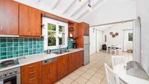 Een keuken met houten kastjes, een roestvrijstalen koelkast en een raam met uitzicht op groen.