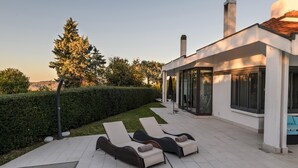 Une terrasse extérieure moderne, dotée de chaises longues et d’un espace clos par des parois de verre.