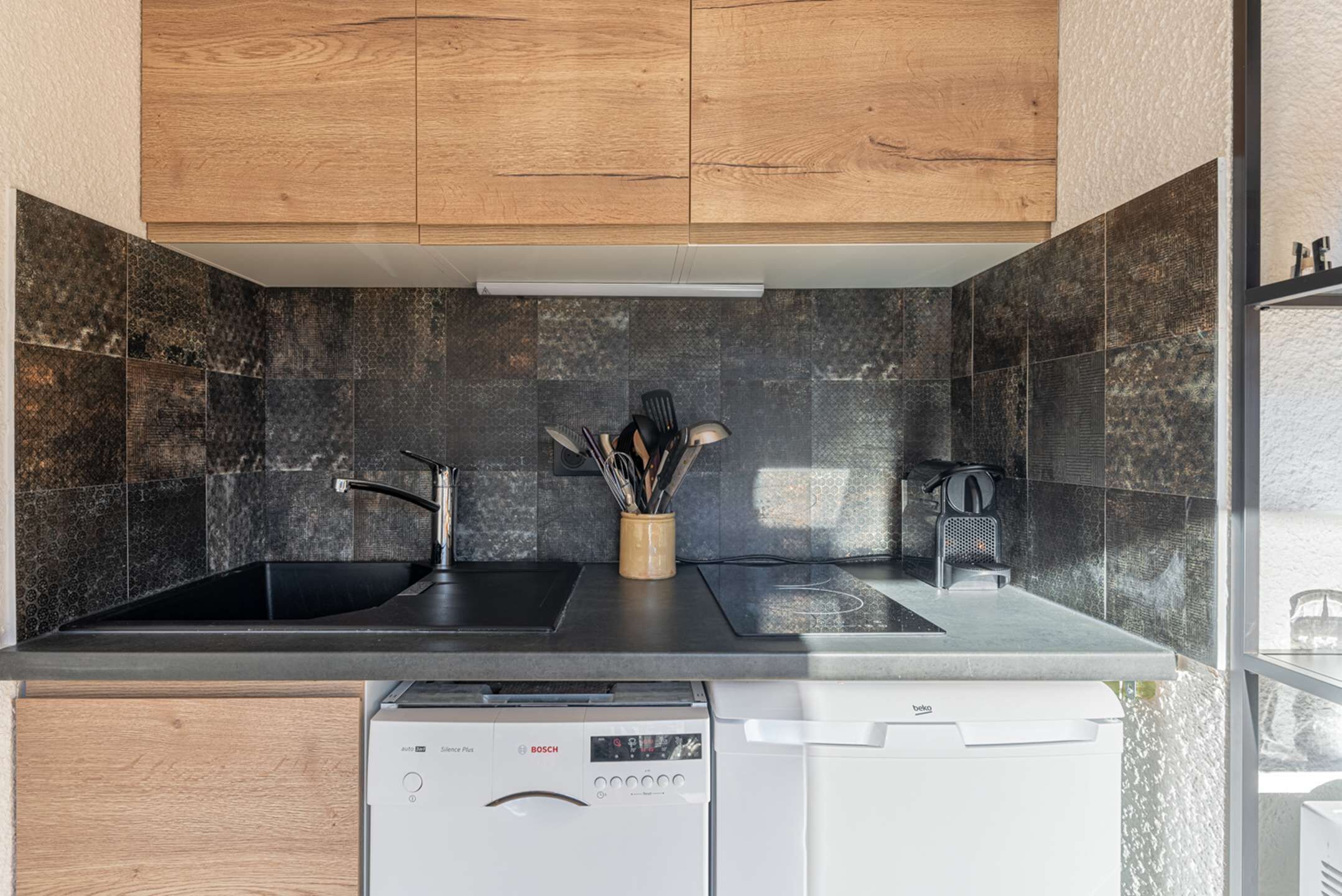 Una cocina moderna con dos fregaderos, un lavavajillas Bosch y un ventanal con vistas.