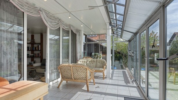Un interior moderno con puertas de vidrio, muebles de mimbre y piso de baldosas.