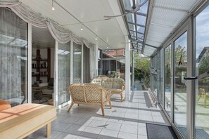 Un interior moderno con puertas de vidrio, muebles de mimbre y piso de baldosas.