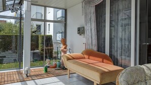 Una sala de estar moderna con un sofá, una escultura de busto y vistas a un jardín a través de ventanas amplias.