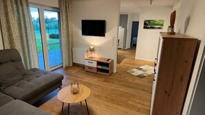 Een moderne woonkamer met een bank, salontafel, televisie en een houten kast.