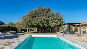 Une piscine dotée d’une pergola et d’un espace salon extérieur.