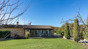 Une maison de plain-pied avec un toit en tuiles, de grandes fenêtres et une pelouse bien entretenue.