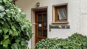 Un bâtiment doté d’une façade à motifs, d’une porte en bois et d’une petite fenêtre ornée d’un rideau.