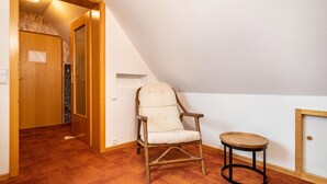 Une pièce comprenant une chaise en bois, une petite table ronde et une porte donnant sur un placard.