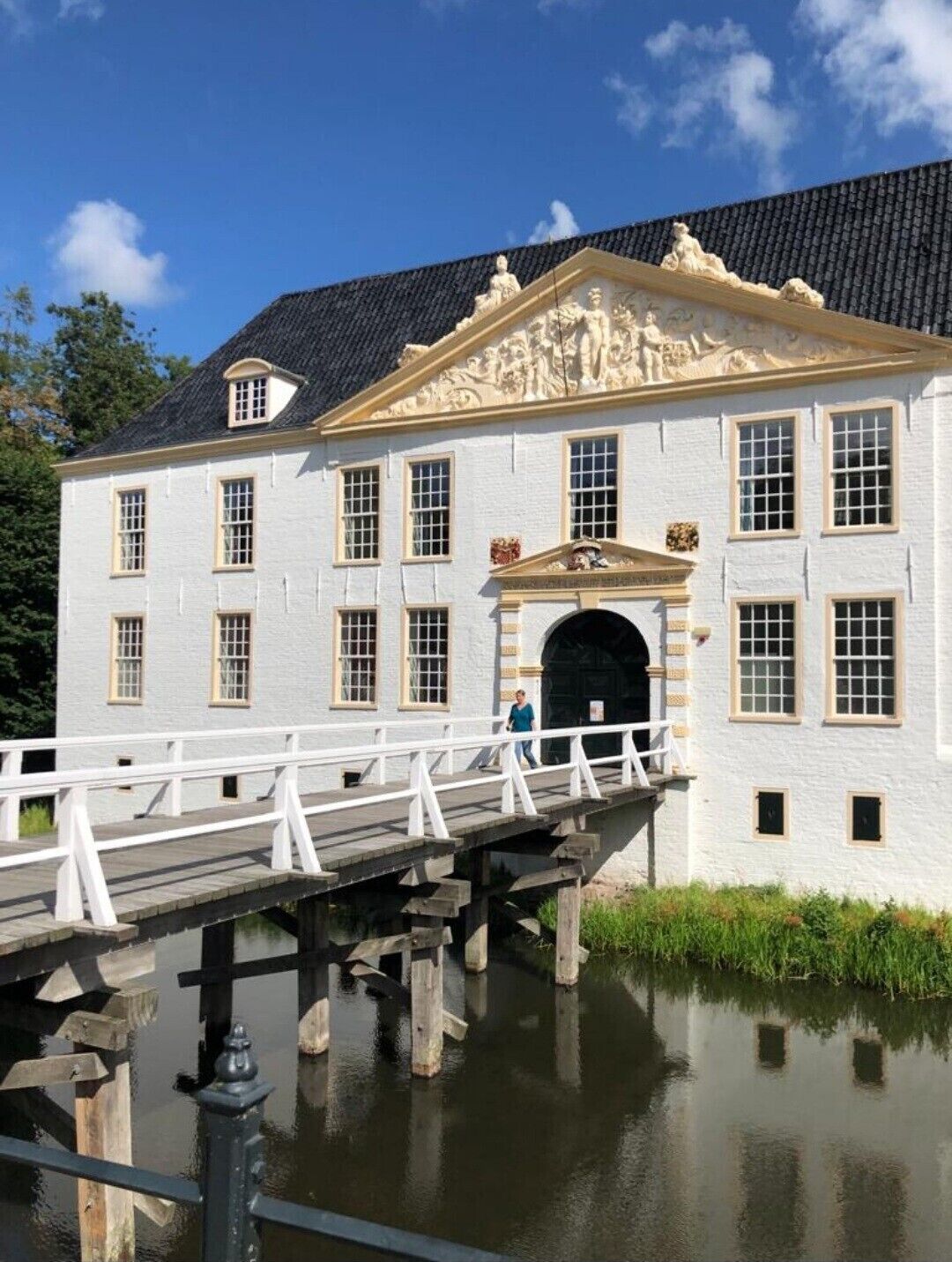 Een wit gebouw met een zwart dak, een brug en een wateroppervlak.